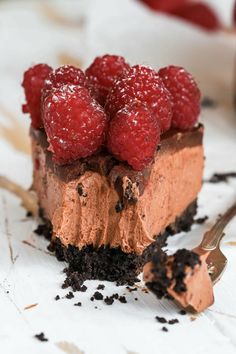 a piece of chocolate cheesecake with raspberries on top and oreo crust