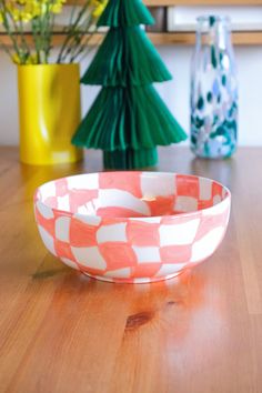 an orange and white bowl sitting on top of a wooden table next to vases