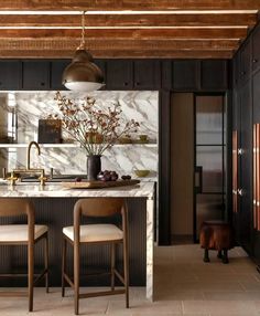 a kitchen with marble counter tops and two stools in front of the bar area