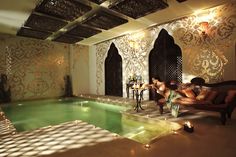 two people sitting on a couch in front of an indoor swimming pool that is lit up with candles