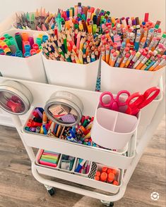 a cart filled with lots of different colored pencils and crayons on top of it