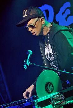 a man standing next to a green turntable on top of a stage in front of microphones