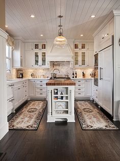 a large kitchen with white cabinets and wood flooring on the walls, along with an island in the middle