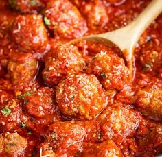 the meatballs are being stirred with marinara sauce and wooden spoon in the pot