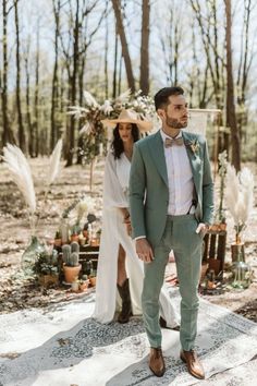 a man and woman standing next to each other in front of a forest with lots of plants