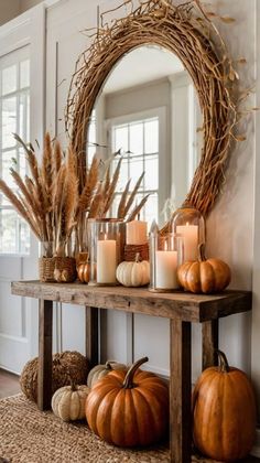 a wooden table topped with candles and pumpkins next to a wreath filled with dry grass