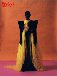 a mannequin wearing a yellow and black dress with an open cape on it