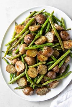 a white plate topped with green beans and potatoes