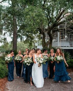 a group of women standing next to each other in front of some trees and bushes