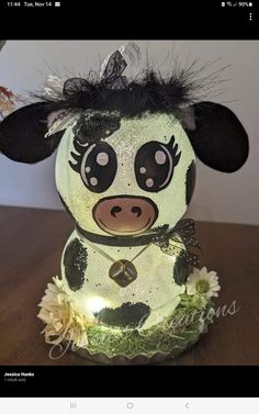 a stuffed cow is sitting on a table with flowers in it's mouth and eyes