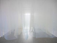 an empty room with sheer curtains on the windows