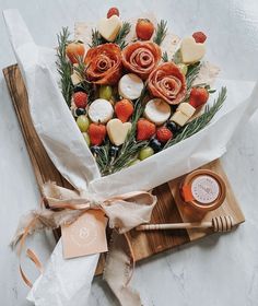 a bouquet of fruit and flowers on top of a cutting board