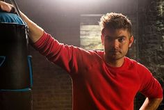 a man standing next to a punching bag