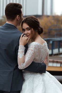 a man in a suit and woman in a white wedding dress are embracing each other