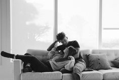 black and white photograph of two people sitting on a couch in front of large windows