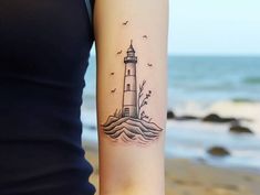 a woman's arm with a lighthouse tattoo on it