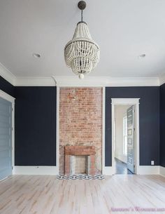 an empty living room with blue walls and white trim on the brick fireplace mantel