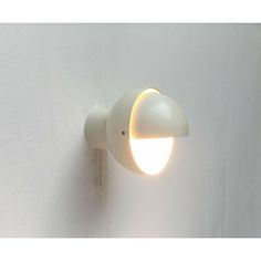 a white wall mounted light on the side of a building with a small round light