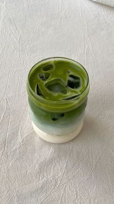 a green cup sitting on top of a white table