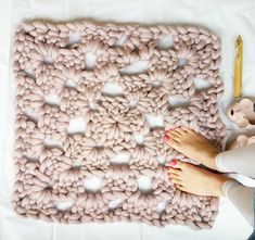 a woman's feet on a pink knitted rug next to a teddy bear