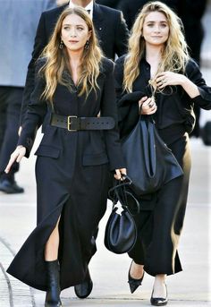 two women in black outfits walking down the street