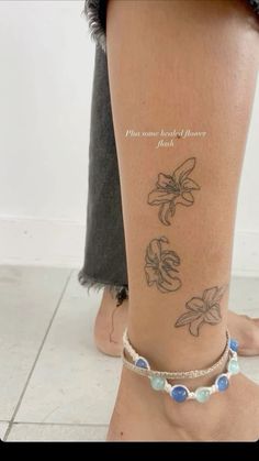 a woman's foot with tattoos on it and flowers tattooed on the side of her leg