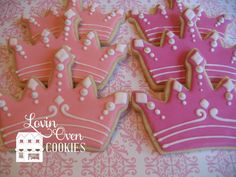 decorated cookies in the shape of crowns on a pink and white tablecloth with damask