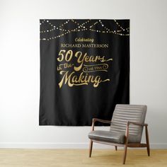 a chair sitting in front of a black and gold 50th birthday banner on a wall