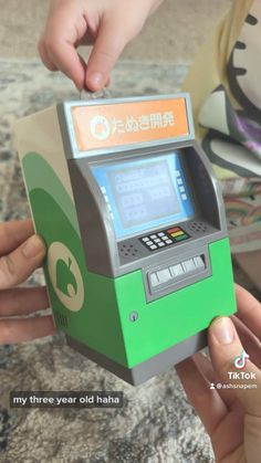 two people are exchanging money from a green and silver atm machine with chinese writing on it