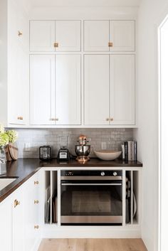 a kitchen with white cabinets and black counter tops