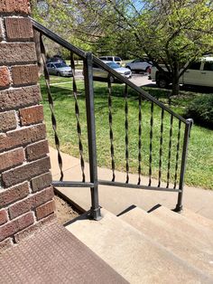 a metal hand rail on the side of a brick building with cars parked in the background