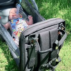 a baby laying in an open suitcase on the grass