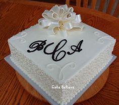 a square cake with white frosting and black letters on it, decorated with a large flower