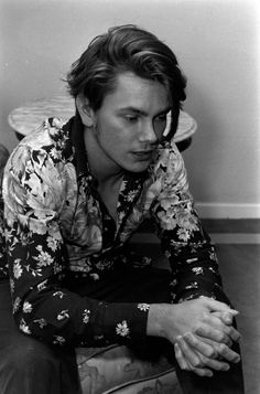 a black and white photo of a man sitting on the floor with his hands together