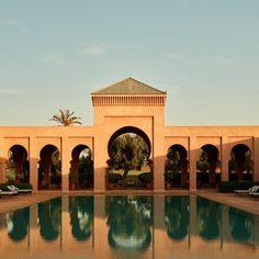 an outdoor swimming pool surrounded by arches and palm trees