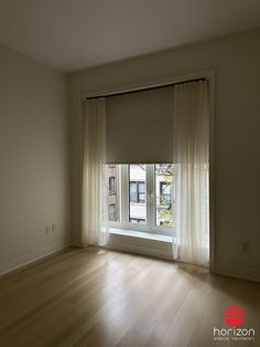 an empty room with wooden floors and white curtains