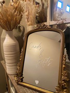 a mirror sitting on top of a table next to vases with dry grass in them