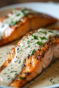 two salmon fillets on a plate covered in sauce