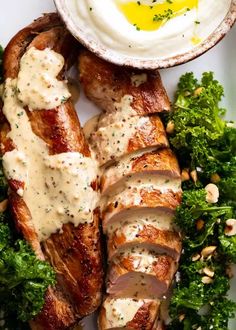 meat and vegetables on a plate with an egg in the middle, along with some ranch dressing