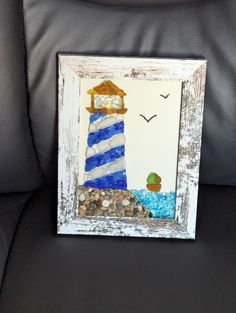 a picture frame with a blue and white lighthouse in the middle on a black couch