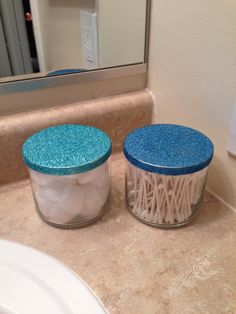 two jars sitting on top of a bathroom counter