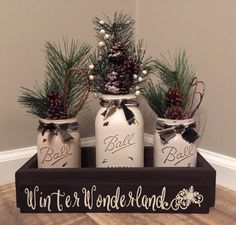 three mason jars with pine cones and bows are sitting on a wooden tray that says winter wonderland