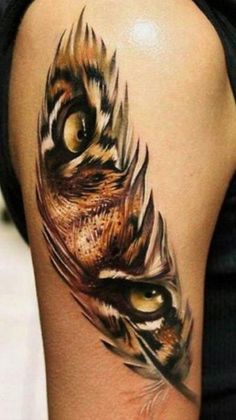 a woman's thigh with an owl feather tattoo on her leg and the eye is open