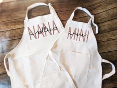 two personalized aprons sitting on top of a wooden table