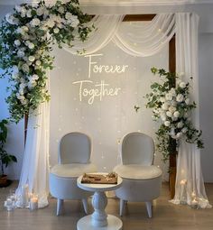 two white chairs sitting in front of a sign that says forever together