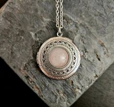 A pale pink rose quartz centered on an intricate antique silver filigree and a frame set on an antique silver locket. Locket hangs from an antique silver chain. Locket opens with 2 spaces for pictures or things as shown.  Details: Locket measures 32mm in diameter Locket has a smooth back  Locket and chain are plated brass Necklace measures 24 inches  Stone is genuine rose quartz Want a shorter chain? Just leave a note to seller at checkout for me and I can adjust it for you, no extra charge.  Thank you for shopping Delicate Industry :) Bohemian Silver Locket Necklace, Bohemian Silver Rose Quartz Necklaces, Bohemian Silver Rose Quartz Necklace, Bohemian Silver Necklace With Rose Quartz, Pink Engraved Pendant Jewelry, Antique Pink Jewelry For Gift, Engraved Pink Pendant Jewelry, Bohemian Silver Rose Quartz Jewelry, Ornate Pink Jewelry Gift