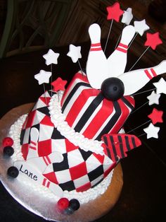 a bowling cake is decorated with red and white icing, black pins, and stars