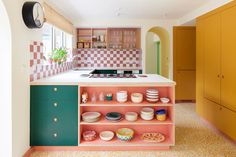 a kitchen with pink and green cabinetry, white counter top and yellow cabinets in the background