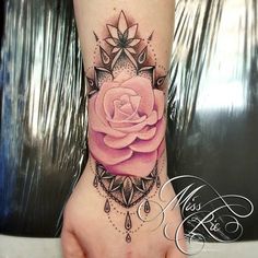 a pink rose tattoo on the wrist and hand with an intricate pattern around it's center