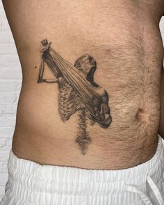 a man with a skeleton tattoo on his stomach holding a scapula in the shape of a cross